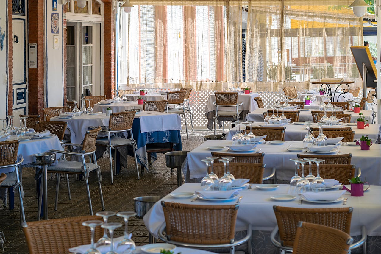 The Art of Drawing Readers In: Your attractive post title goes here Charming outdoor dining area with neatly set tables in Sitges, Spain, bathed in natural light.